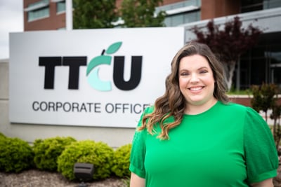 Woman standing outside of TTCU sign