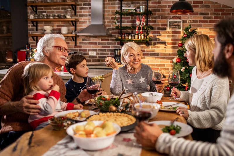 Familia sentada alrededor de la mesa disfrutando de la cena navideña