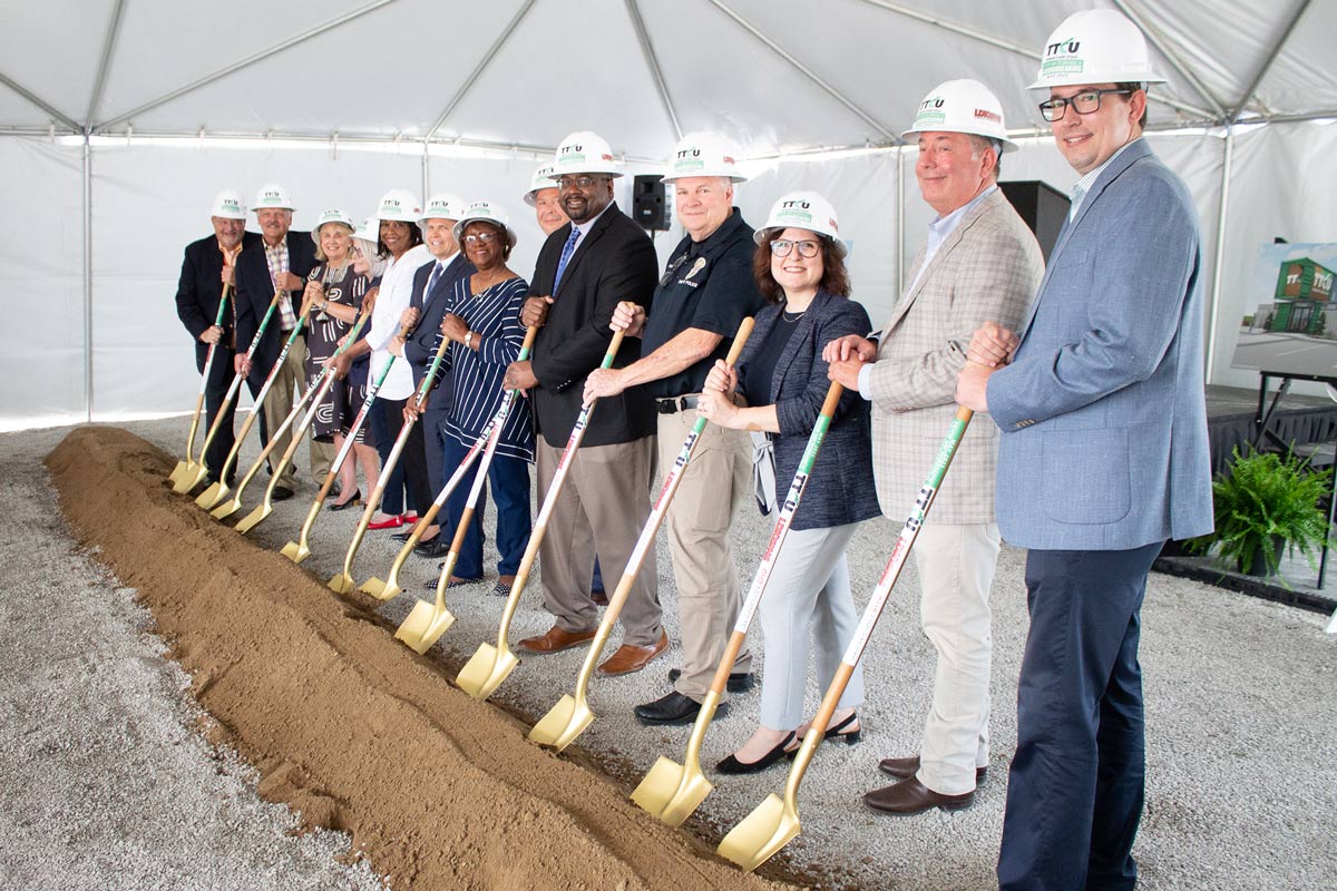 Group of people standing behind dirt with shovels