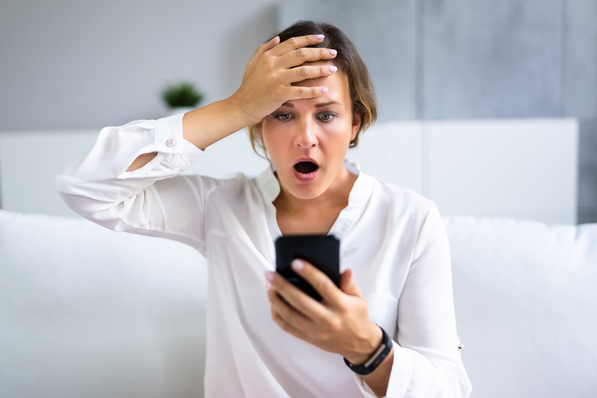 Mujer sosteniendo el teléfono con cara de asombro