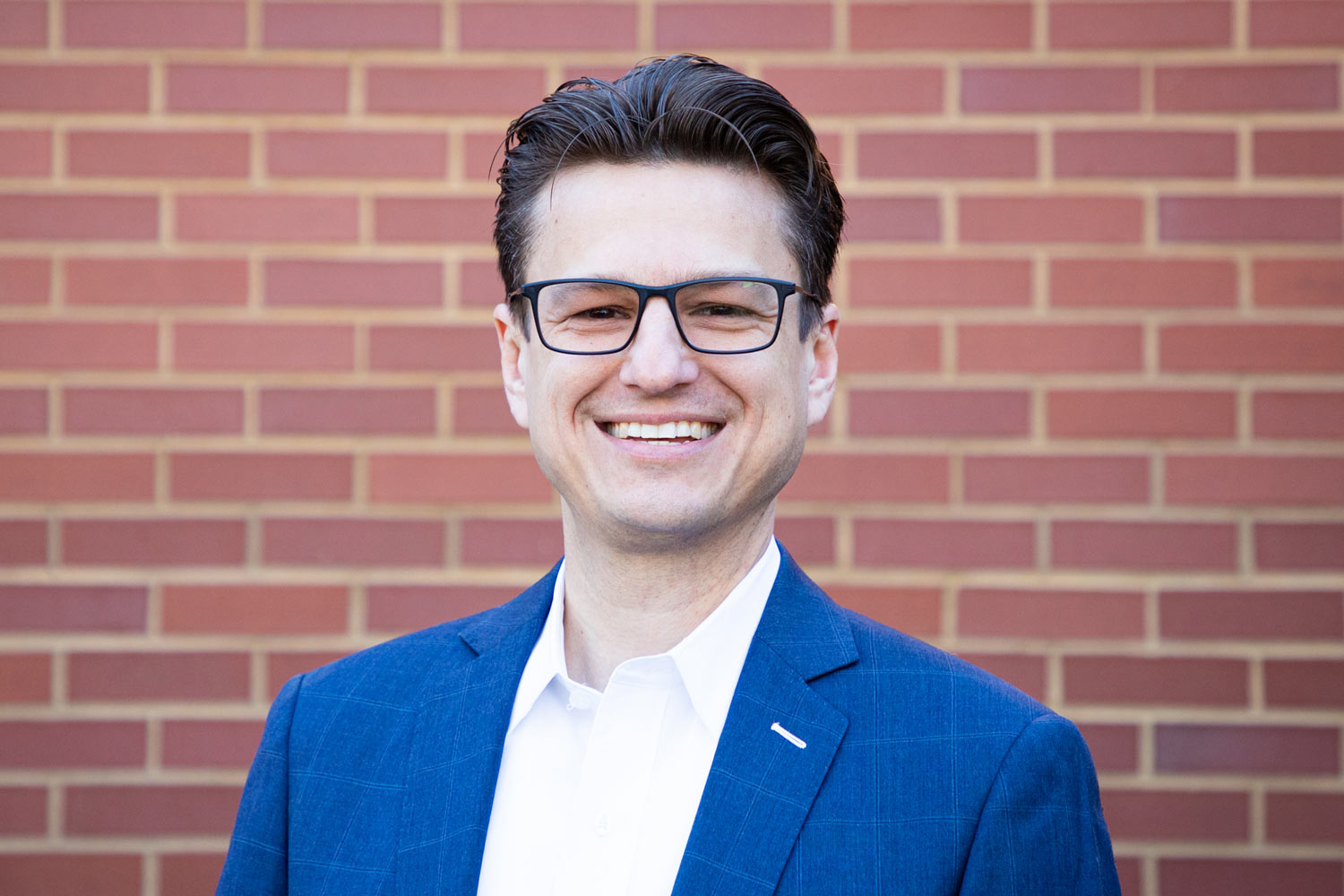 Justin_Headshot Man standing in front of brick wall